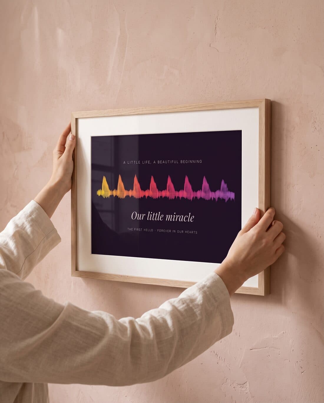 Hands hanging a framed heartbeat print on a wall