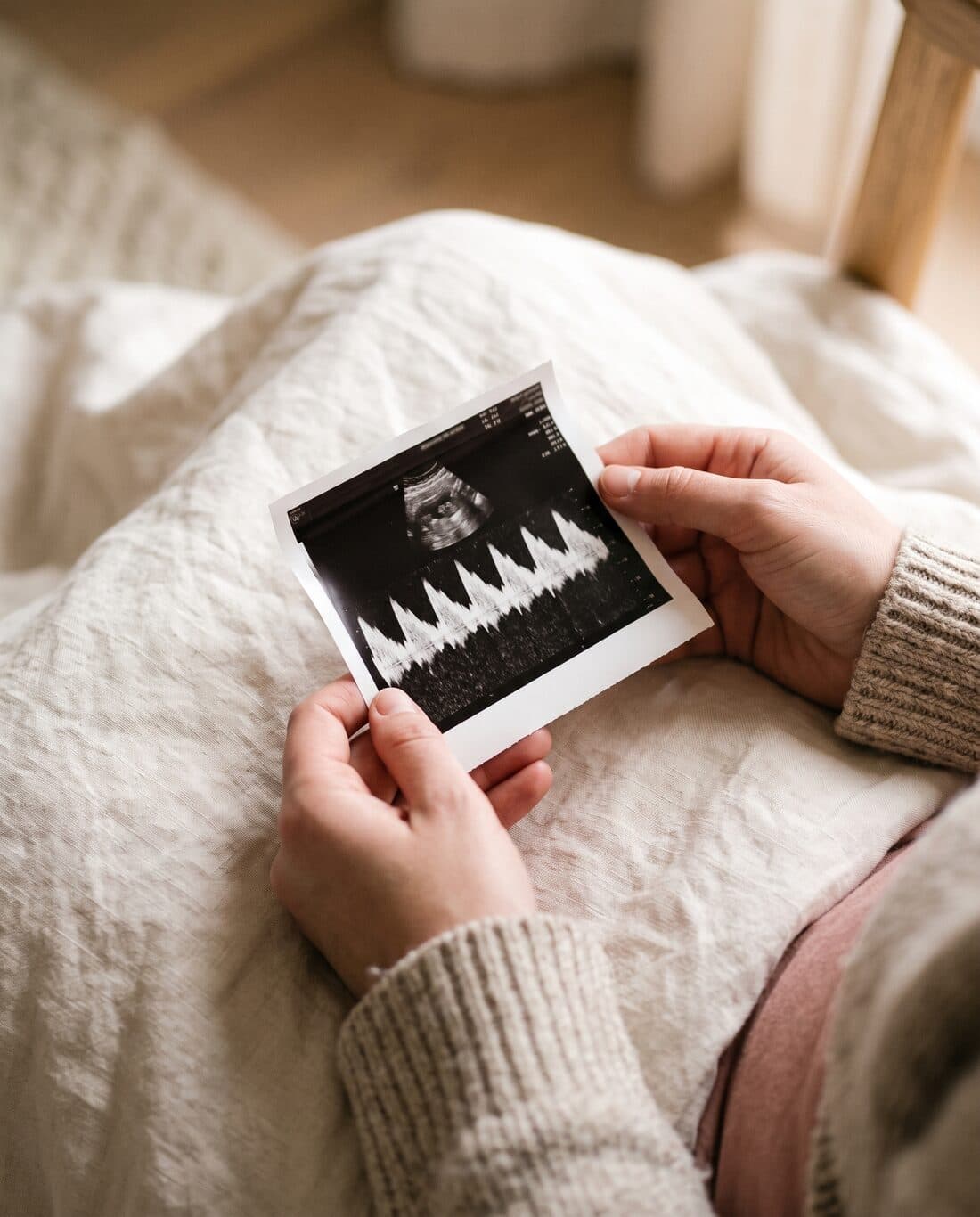 Hands holding an ultrasound printout with a heartbeat trace